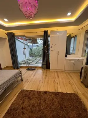 a living room with a bed and a wooden floor at Serene Hills in Ooty