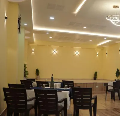 a dining room with a blue table and chairs at Coastal Grand Resorts - Akshaya in Kotagiri