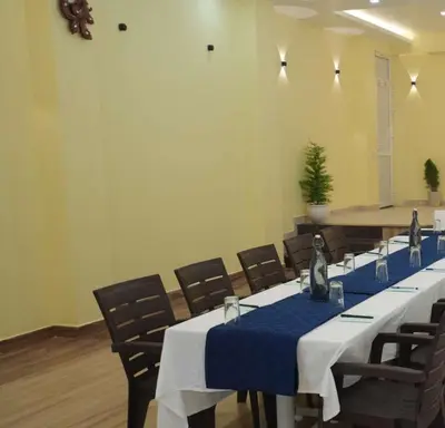 a conference room with a long table with blue table cloth at Coastal Grand Resorts - Akshaya in Kotagiri