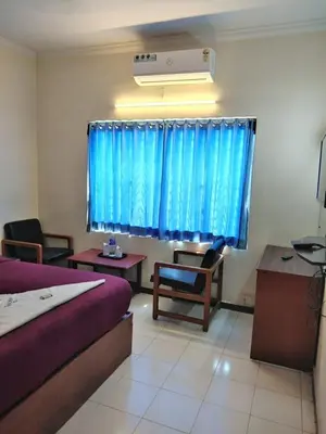 a bedroom with a bed and chairs and a window at Asoka Inn in Mettuppālaiyam