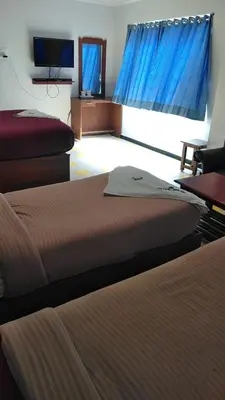 a hotel room with two beds and a television at Asoka Inn in Mettuppālaiyam