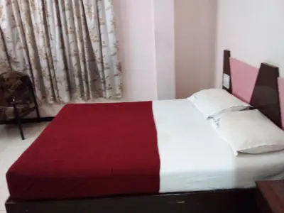 a bedroom with a bed with a red and white blanket at Asoka Inn in Mettuppālaiyam