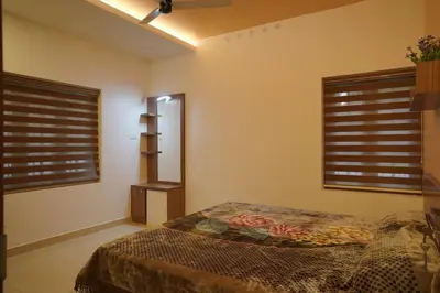 a bedroom with a bed and two windows with blinds at Home stay - Near Cochin Airport in Angamali