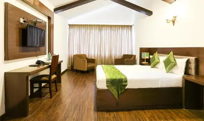 a hotel room with a bed and a desk and a computer at Treebo Skydale Inn & Suites With Mountain View in Ooty