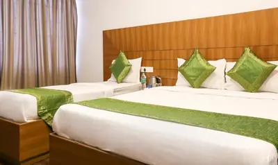 two beds in a hotel room with green pillows at Treebo Skydale Inn & Suites With Mountain View in Ooty