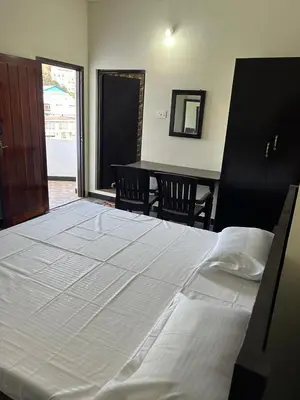 a large white bed in a room with a table at Arulmozhi Dream in Ooty