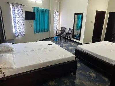a bedroom with two beds and a tv and chairs at Arulmozhi Dream in Ooty