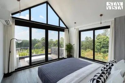a bedroom with a large bed and large windows at StayVista at Lotus Lumiere with Breakfast & jacuzzi in Madikeri