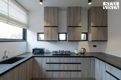 a kitchen with wooden cabinets and a stove at StayVista at Lotus Lumiere with Breakfast & jacuzzi in Madikeri