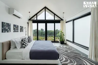 a bedroom with a bed and a large window at StayVista at Lotus Lumiere with Breakfast & jacuzzi in Madikeri