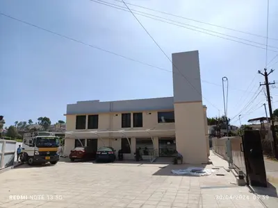 a building with a bus parked in a parking lot at Arasan Residency in Kotagiri