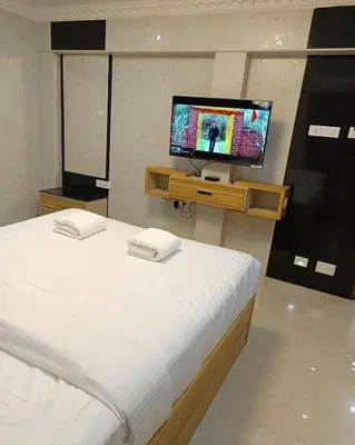 a bedroom with a bed with a television on a table at Arasan Residency in Kotagiri
