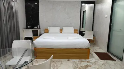 a bedroom with a bed with a glass table and chairs at Arasan Residency in Kotagiri