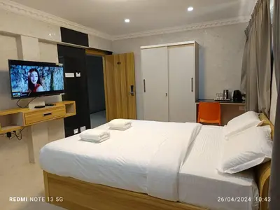 a bedroom with a large white bed and a flat screen tv at Arasan Residency in Kotagiri