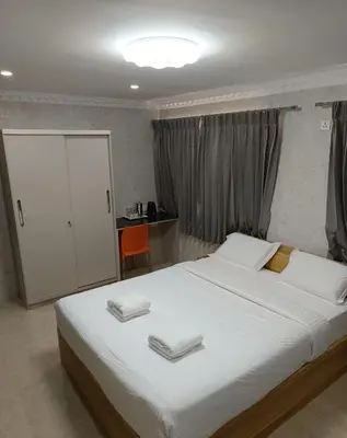 a bedroom with a large bed with two towels on it at Arasan Residency in Kotagiri