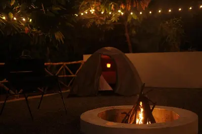 a tent and a fire pit in a yard at night at Nila Paithal in Paithalmala