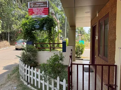 a white picket fence in front of a building with a sign at Rest House @ Merlys Fruit Garden in Thattakād