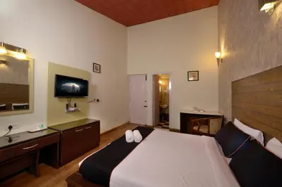 a bedroom with a large bed and a television at Sabol Holidays in Ooty