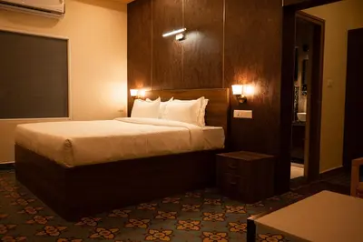 a hotel room with a bed and a table at Poojaris Nirantara - Mysuru in Hampāpura