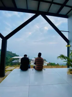 two people sitting on the ground looking at the ocean at Mist View Resort Wayanad in Wayanad