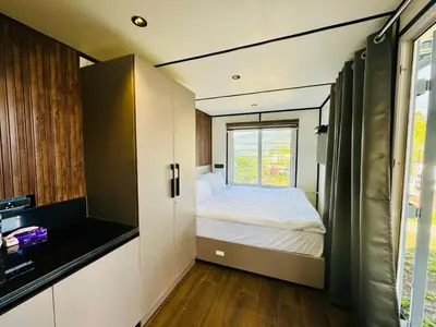 a small bedroom with a bed and a window at The Jade Highlands Mountain View Container Studio Room in Kodaikānāl