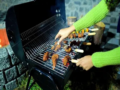 a person is cooking food on a grill at The Jade Highlands Mountain View Container Studio Room in Kodaikānāl