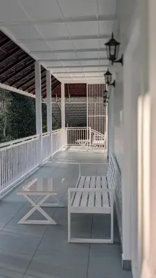 a porch with a bench and a table on it at Meghamalhar in Mānantoddy