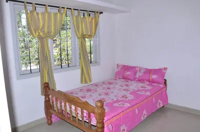 a bedroom with a bed with pink sheets and a window at Sundara vana estate stay madikeri in Madikeri