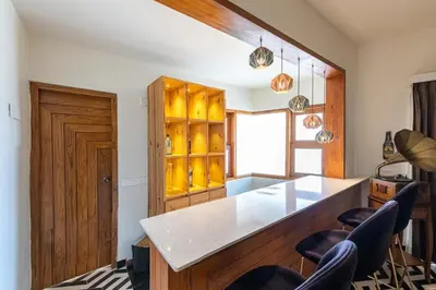 a kitchen with a counter with chairs and a table at Asta in Ooty