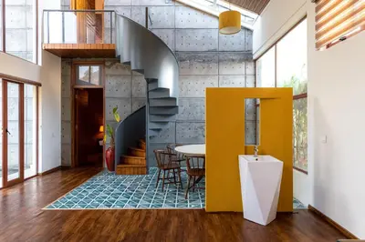 a dining room with a yellow staircase and a table at Asta in Ooty