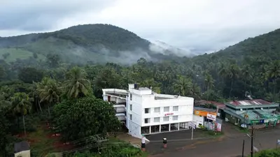 a white building in front of a mountain at Sreeja Myst in Athirappilly