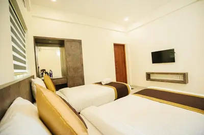 a hotel room with three beds and a television at Sreeja Myst in Athirappilly