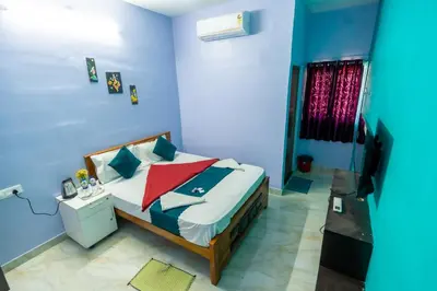 a bedroom with a bed with blue walls and a television at Aryas Residency- Near Isha Foundation Coimbatore & Adiyogi statue in Alāndurai