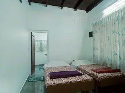 a bedroom with two twin beds and a mirror at Sanctuary View Homestay Thattekad in Ernakulam