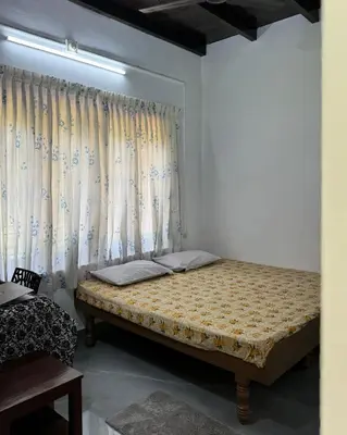 a bed in a room with a curtain at Sanctuary View Homestay Thattekad in Ernakulam