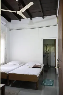 two beds in a room with a ceiling fan at Sanctuary View Homestay Thattekad in Ernakulam