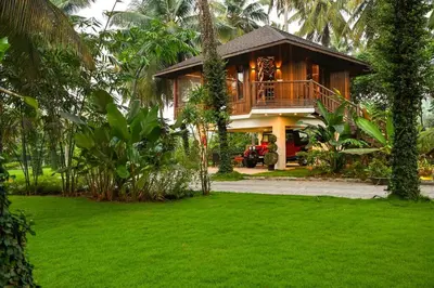 a house with a green lawn in front of it at Villa Woods & Palms in Pollāchi