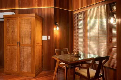 a dining room with a table and chairs and wooden walls at Villa Woods & Palms in Pollāchi