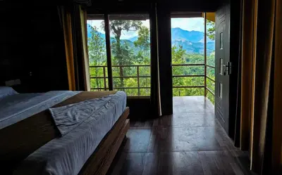 a bedroom with a bed and a balcony with a view at Peter's Coffee Creek Wayanad Pool Resort in Wayanad