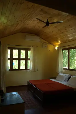 a bedroom with a bed in a room with windows at Aranyasun in Masinagudi