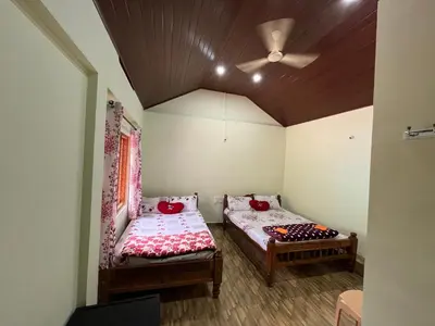 two beds in a room with a ceiling fan at cocostay coorg in Madikeri