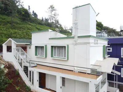 a white house with a staircase on the side of it at Casa de Selas in Coonoor
