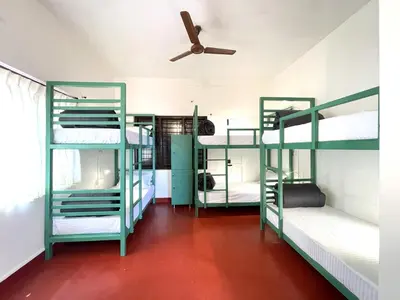 a room with three bunk beds with a ceiling fan at ABODE Backpacker's Hostel in Madikeri