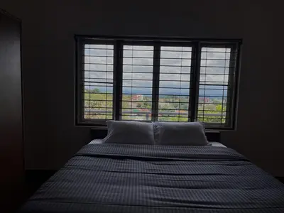 a bed in a room with a large window at ABODE Backpacker's Hostel in Madikeri
