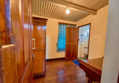 an empty hallway with a wooden door and a window at Vintage Inglenook Premium Heritage Bungalow Ooty by VOYE HOMES - A Quiet Retreat Close to Ooty Town in Ooty