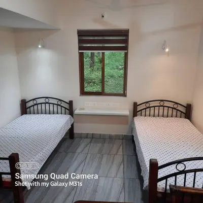two beds in a room with a window at Farm stay in a coffee plantation near Athirappally in Kodali