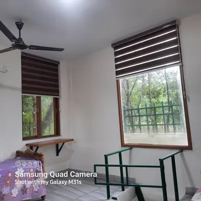 a room with two windows and a bed and a fan at Farm stay in a coffee plantation near Athirappally in Kodali