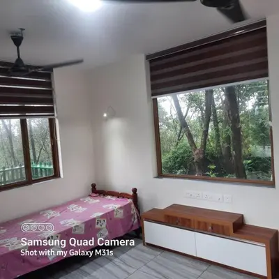 a bedroom with a bed and two large windows at Farm stay in a coffee plantation near Athirappally in Kodali