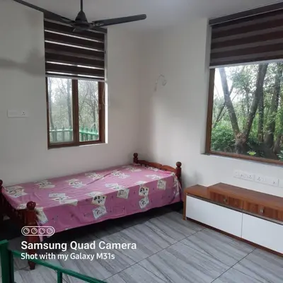 a bedroom with a bed in a room with windows at Farm stay in a coffee plantation near Athirappally in Kodali