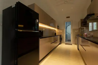 a kitchen with a black refrigerator and a hallway at Ocean Whisper- psst! hidden gem in Kaipamangalam